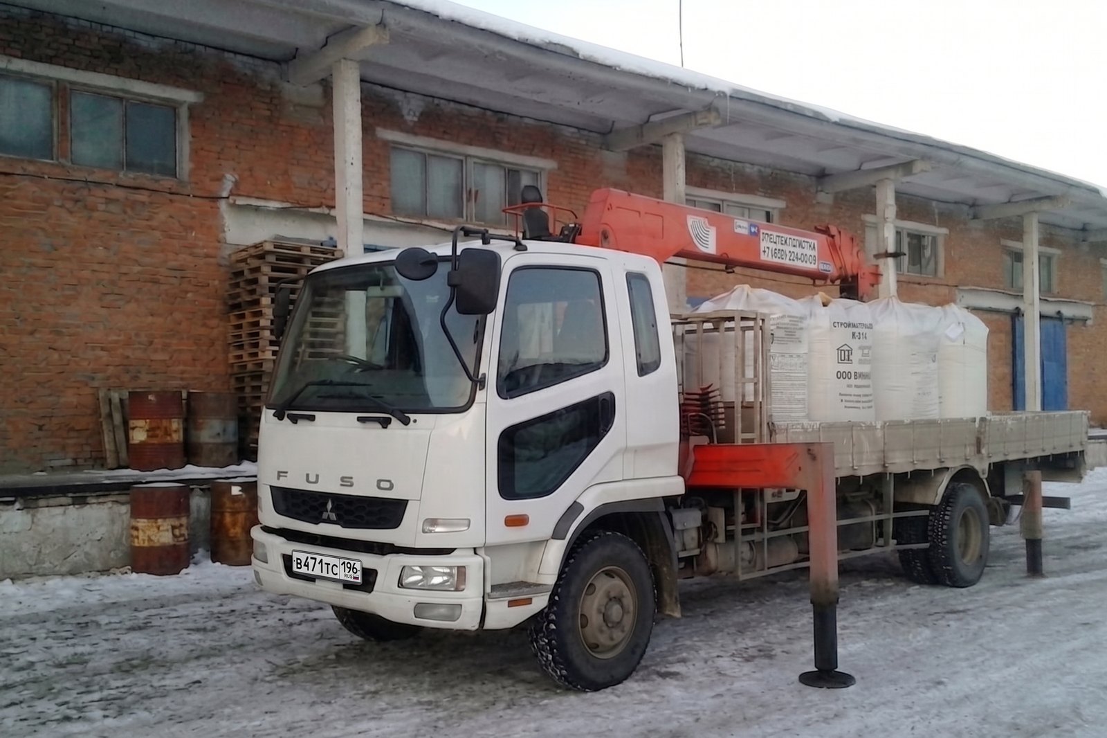 Манипулятор Mitsubishi Fuso с краном на площадке базы, на кузове мешки со стройматериалами
